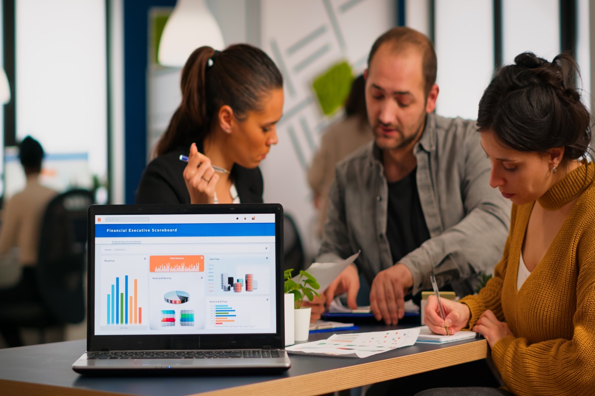 business-woman-talking-about-financial-project-taking-notes-discussing-start-up-ideas-using-laptop-diverse-employees-gathered-co-working-working-process-busy-company-teamwork-help-concept (1)