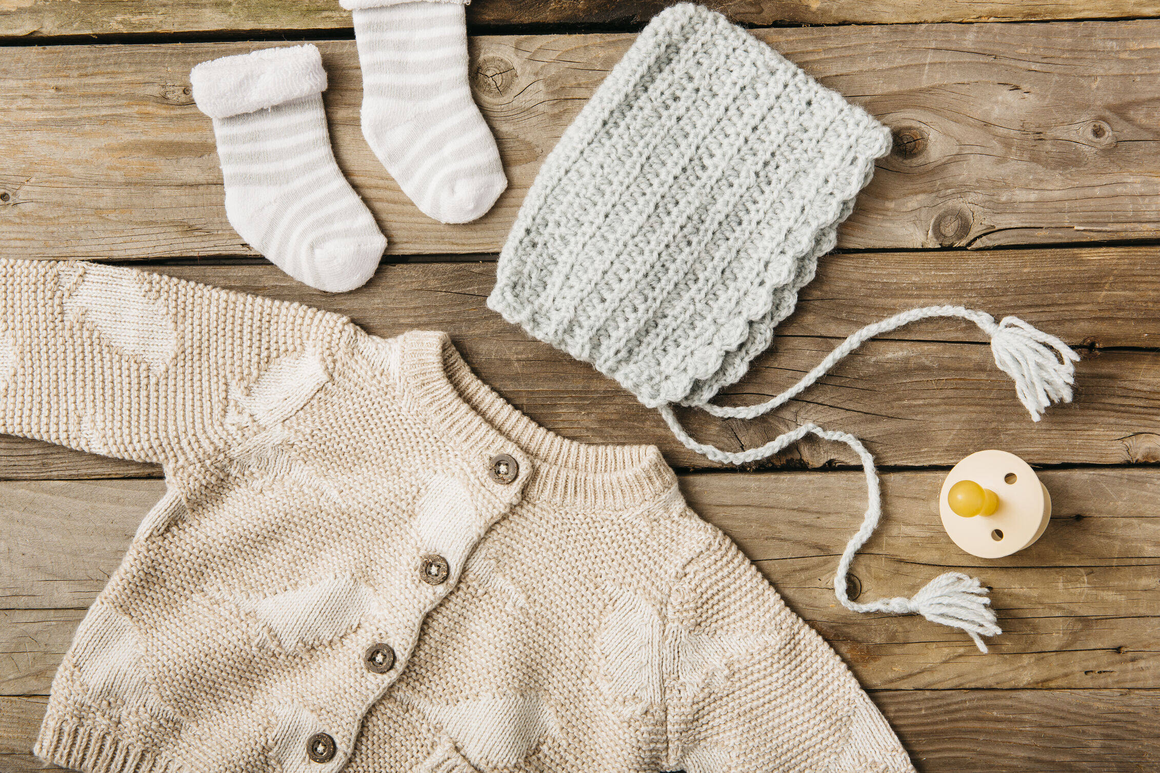 overhead-view-woolen-baby-s-clothing-with-pacifier-wooden-table_optimized_1000